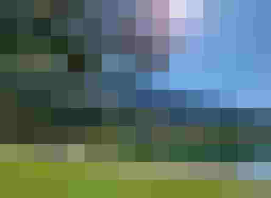 sonniger Badesee mit Wiese, Spielplatz und bewaldeten Bergen im Hintergrund